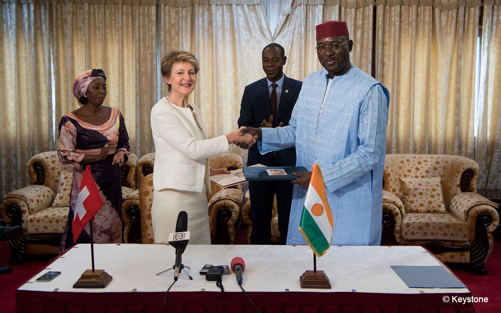 Bundesrätin Simonetta Sommaruga und Nigers Aussen-, Kooperations- und Integrationsminister Ibrahim Yacouba stehen nach der Unterzeichnung des Abkommens zur Unterstützung ländlicher Organisationen an einem Tisch und geben sich die Hand