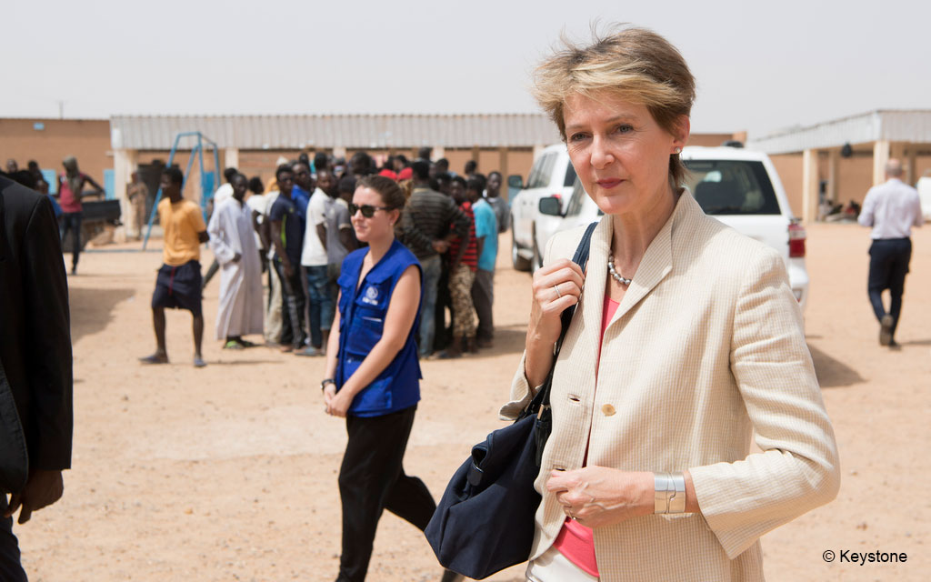 Bundesrätin Simonetta Sommaruga besucht das Empfangs- und Transitzentrum der Organisation IOM in Agadez. Im Hintergrund sind Migranten und Baracken des Lagers zu sehen.