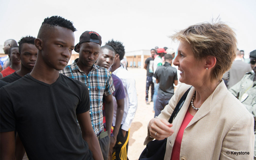 La consigliera federale Simonetta Sommaruga visita un centro d’accoglienza e di transito dell’organizzazione IOM ad Agadez, Niger. L’immagine la mostra mentre dialoga con giovani migranti.