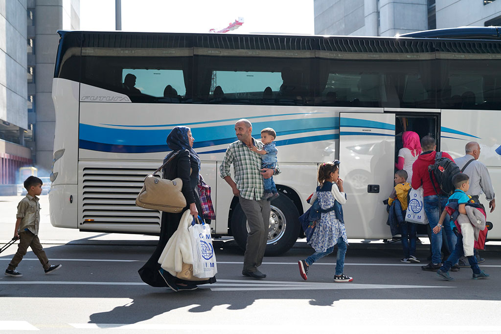 Une famille syrienne avec trois enfants monte dans un bus à l’aéroport de Zurich, avec d’autres réfugiés à réinstaller.